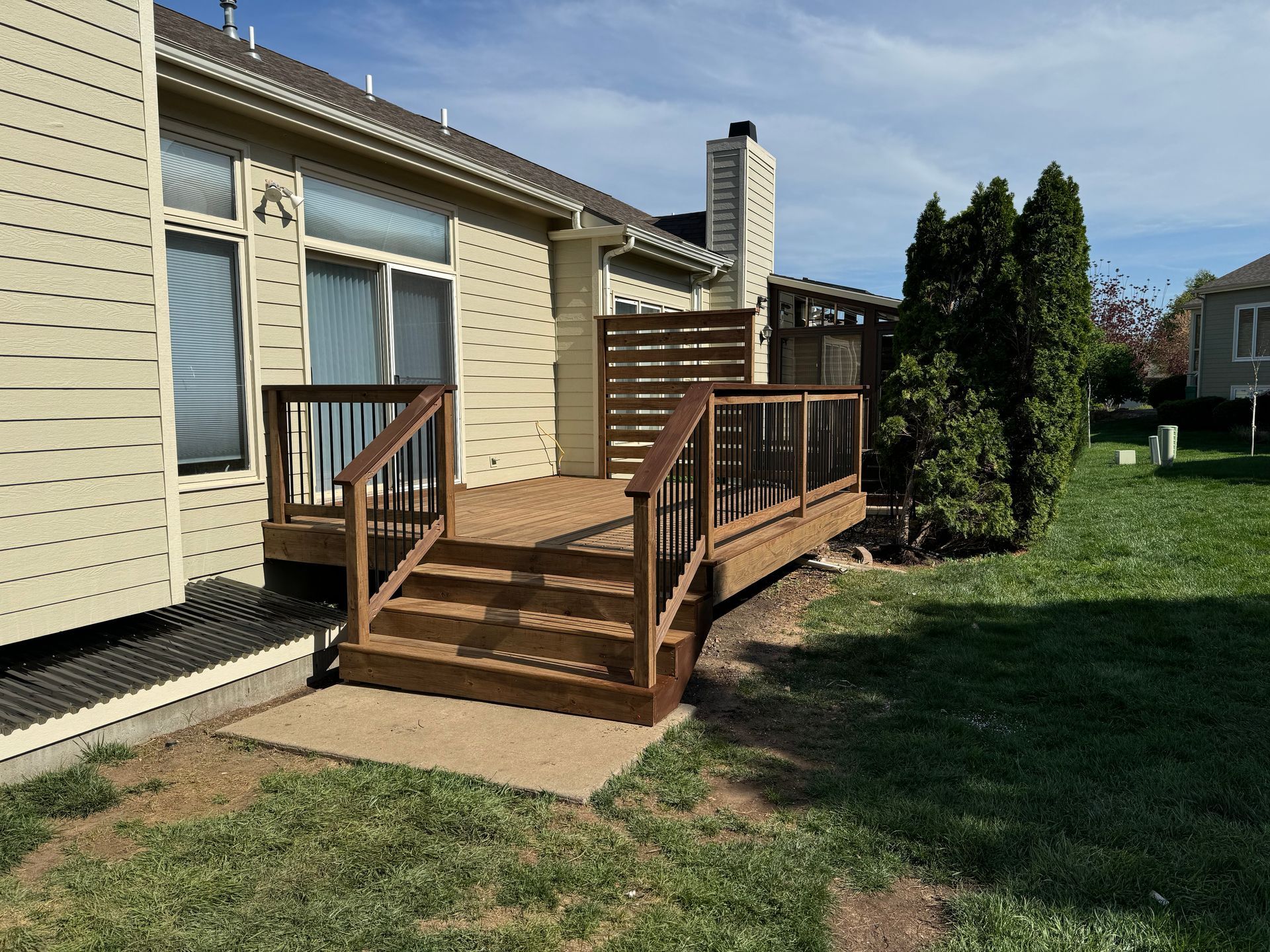 Wooden accessibility ramp and deck beside a beige house on a grassy yard
