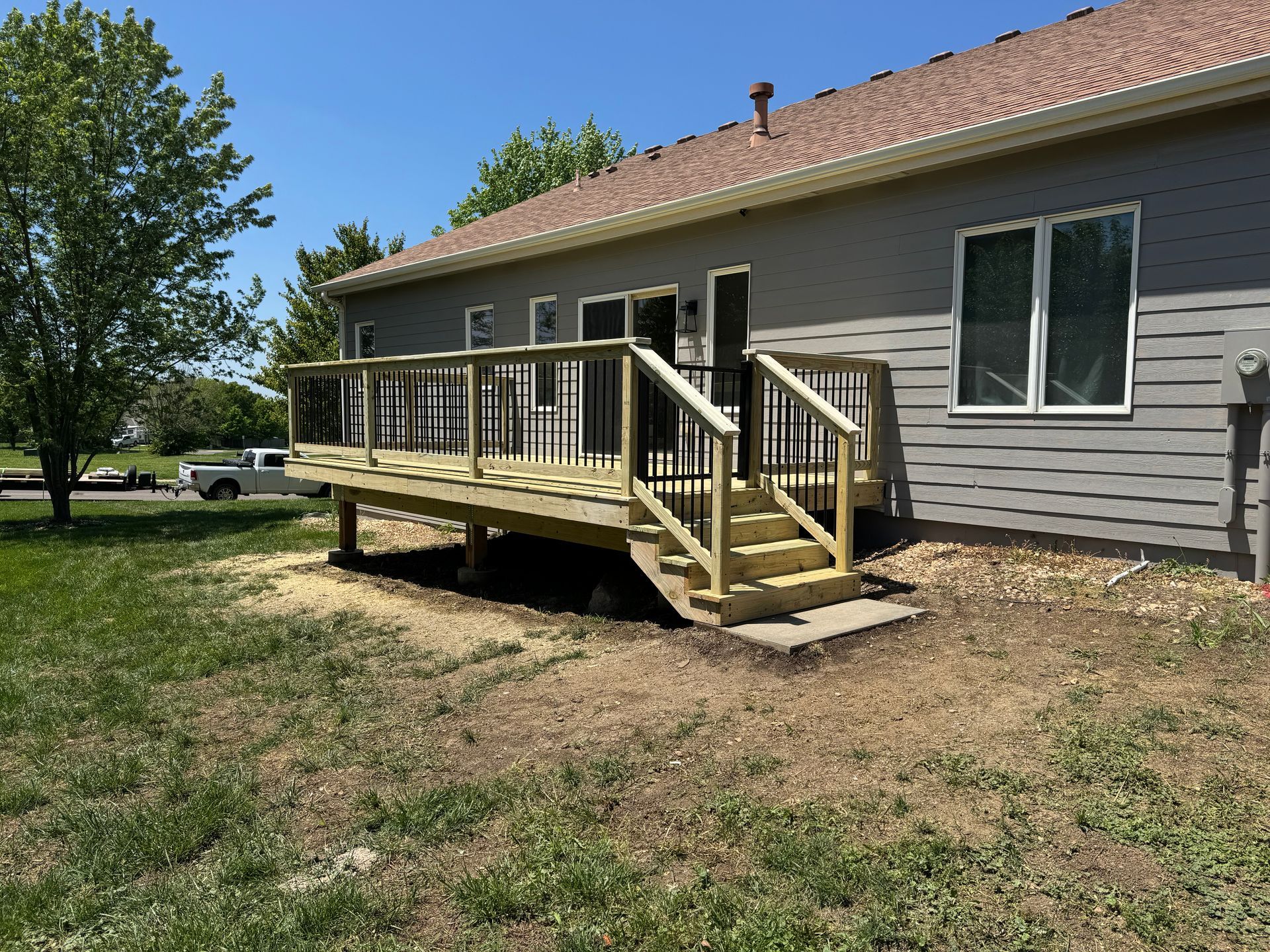 Single-story house with a small wooden porch ramp and railing in a grassy yard