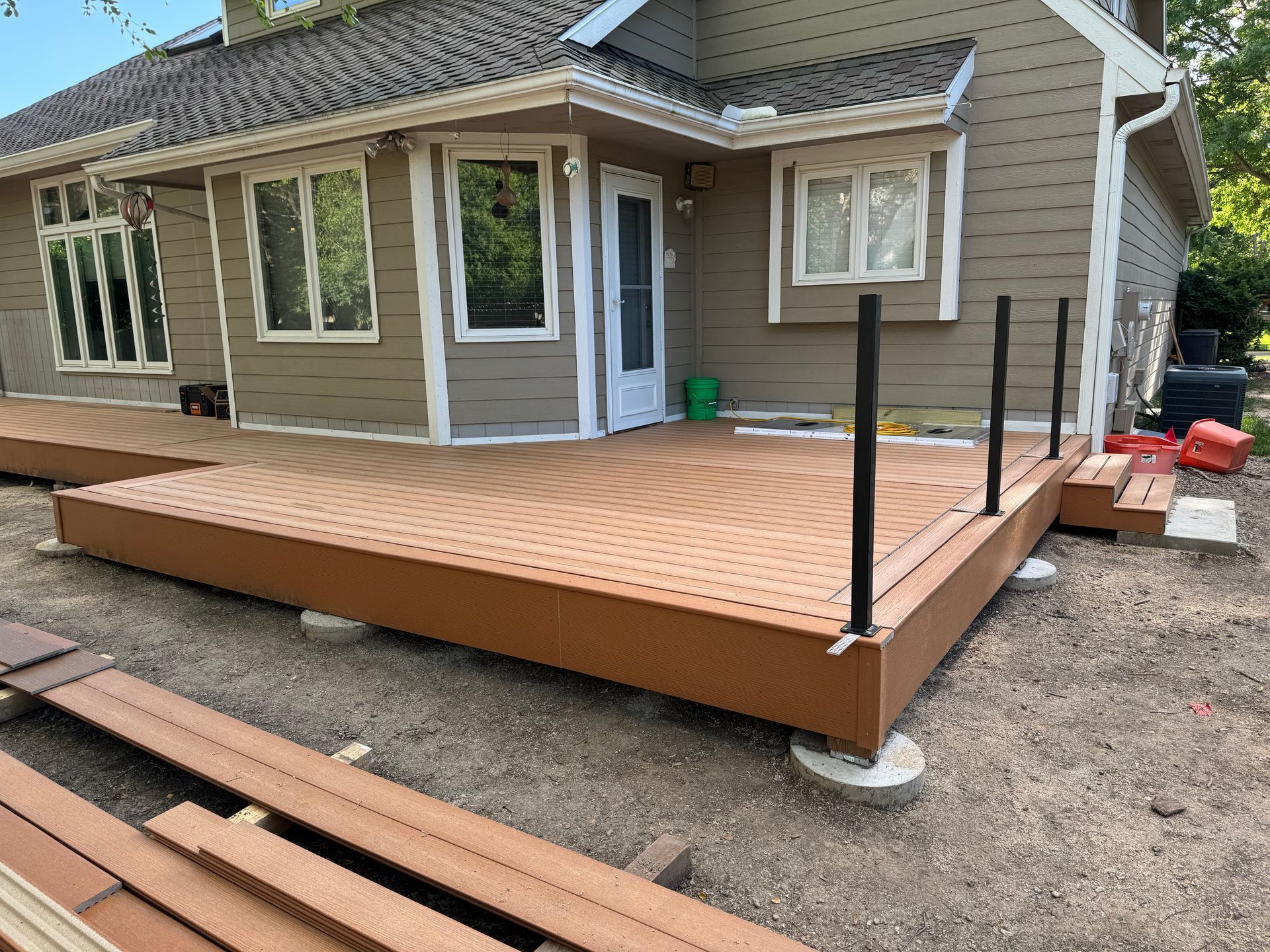 New wooden accessibility ramp with black railings beside a house under construction