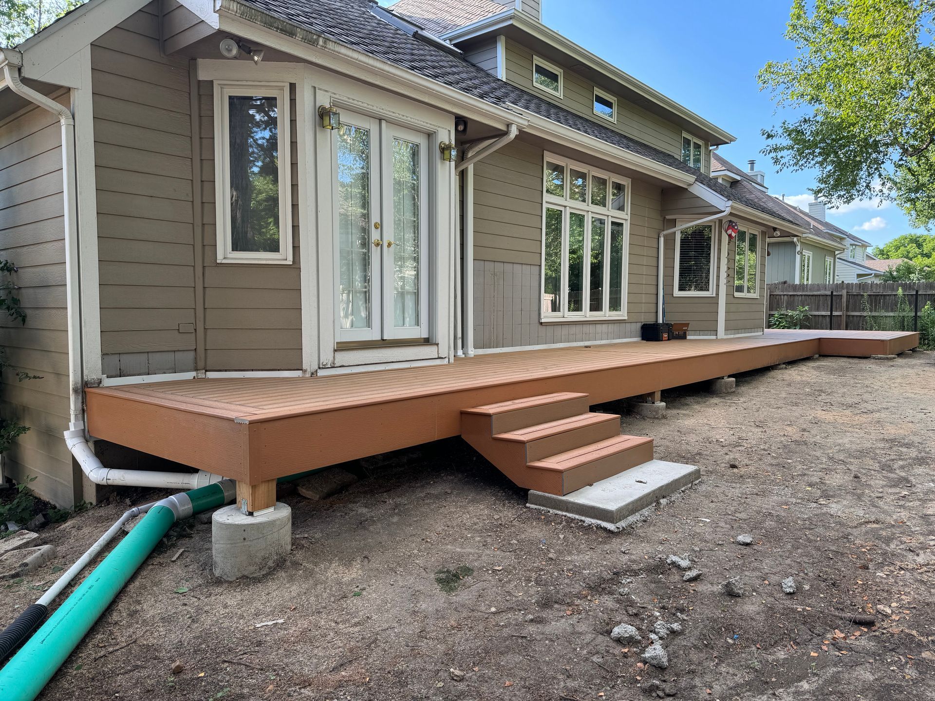 Backyard house deck under construction with steps and gravel ground