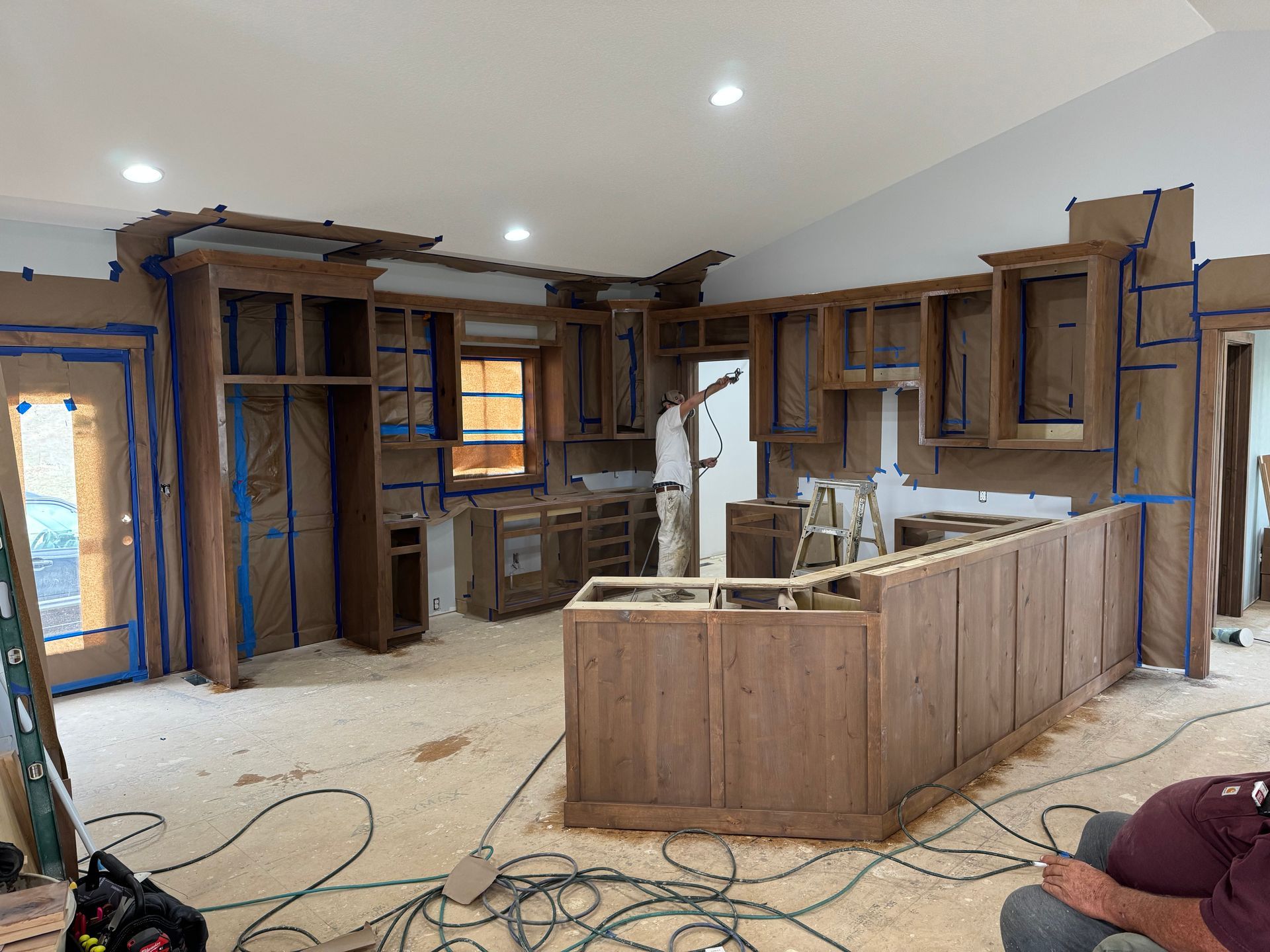 Kitchen under renovation with exposed wooden cabinets, unfinished island, and construction tools on the floor