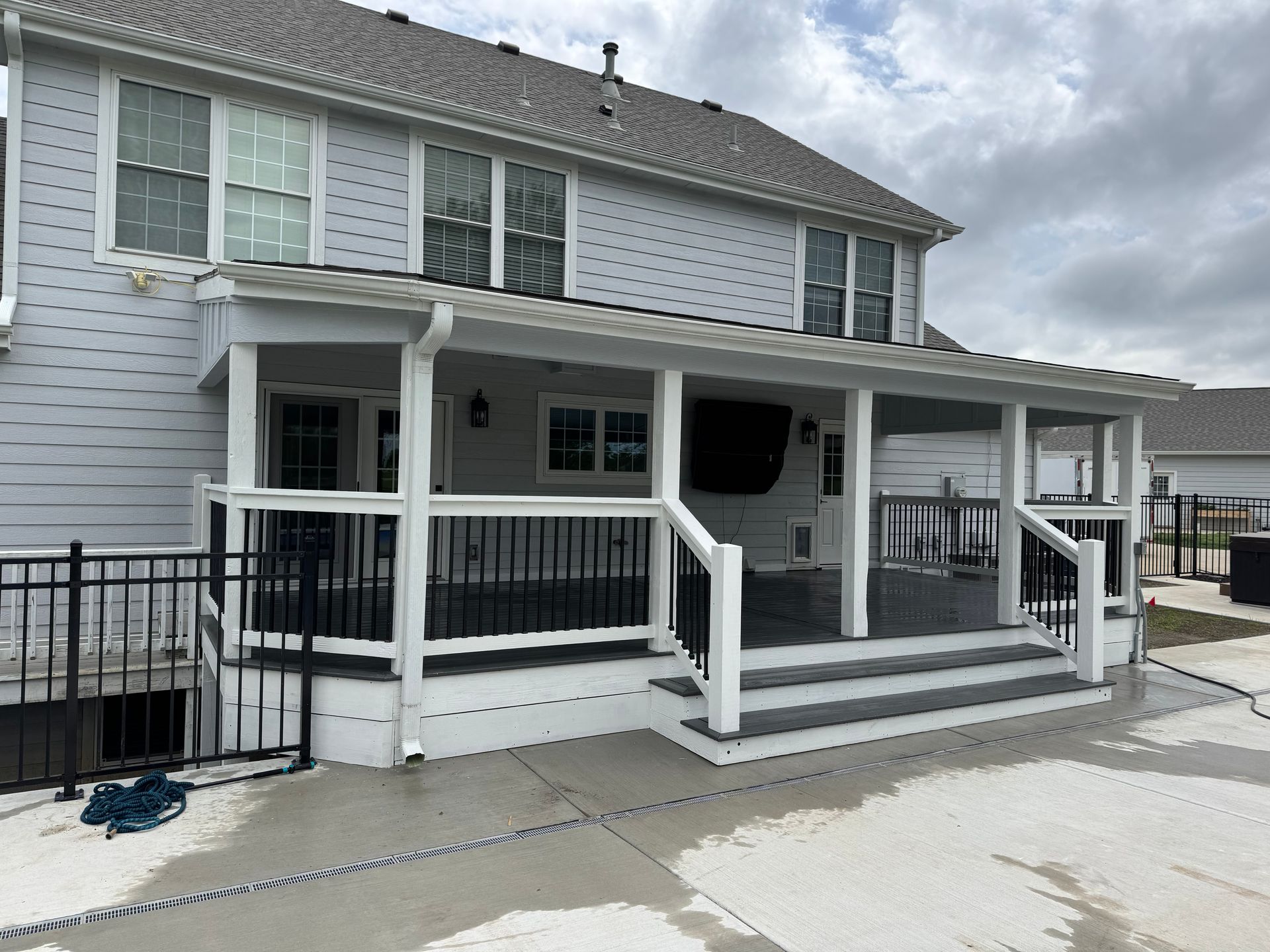 White two-story house with a covered front porch, steps, and railings beside a driveway