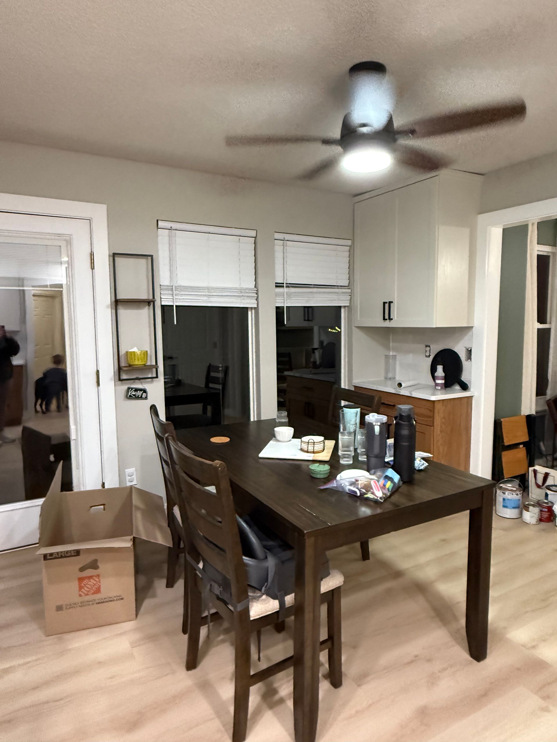 Dining room with a table, chairs, cardboard box, and ceiling fan in a home interior.
