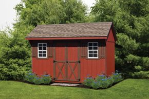 Red garden shed with white-trimmed windows and doors, surrounded by grass, flowers, and trees.