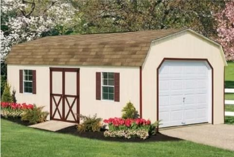 Small cream garden shed with brown trim and white garage-style door, surrounded by flowers.