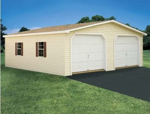 Beige detached garage with two white doors and brown windows on a grassy lot