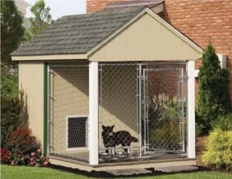 Small beige outdoor pet kennel with a chain-link run and a black dog inside in a yard.