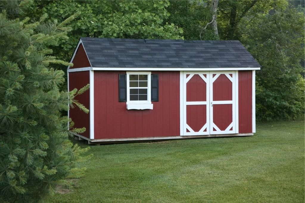 Red garden shed with white trim and double doors in a grassy yard surrounded by trees