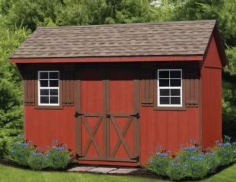 Red garden shed with double doors, white-trimmed windows, and flower beds in front of green trees.