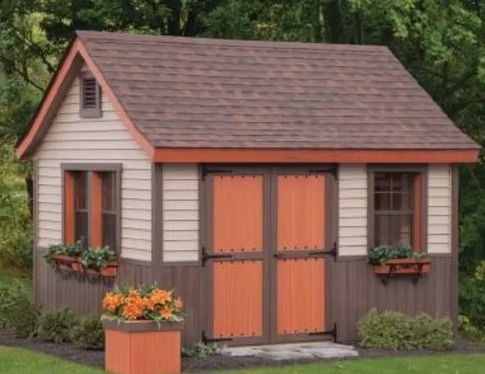 Small beige garden shed with orange doors, brown roof, and flower boxes beside a lawn.