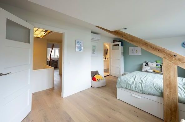 Een slaapkamer met twee bedden en een houten balk in het plafond.