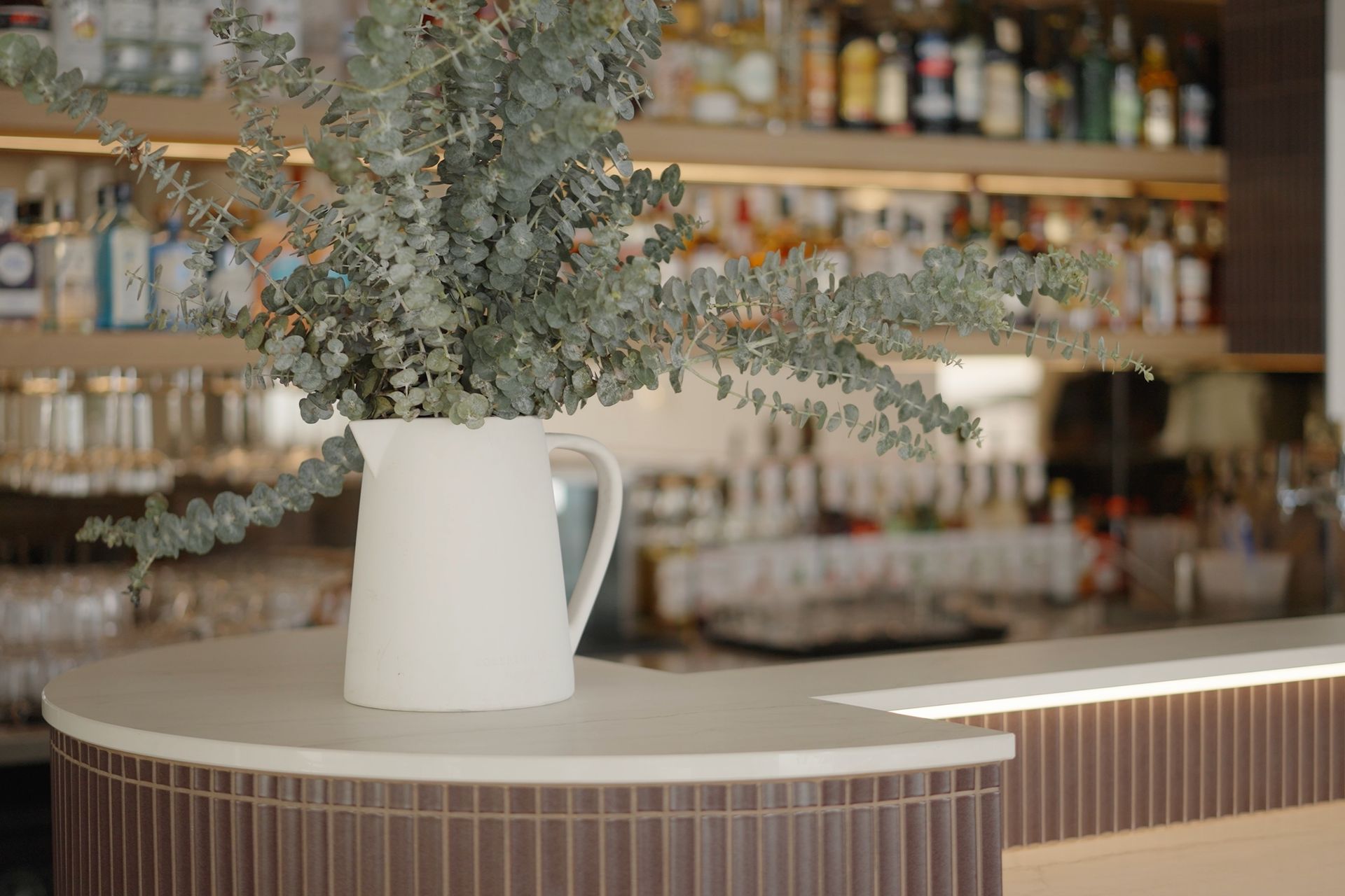 Tiled front bar and counter detail with floral arrangement and shelving