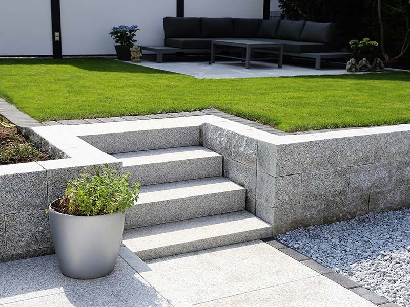 A potted plant sits next to a set of stairs in a garden