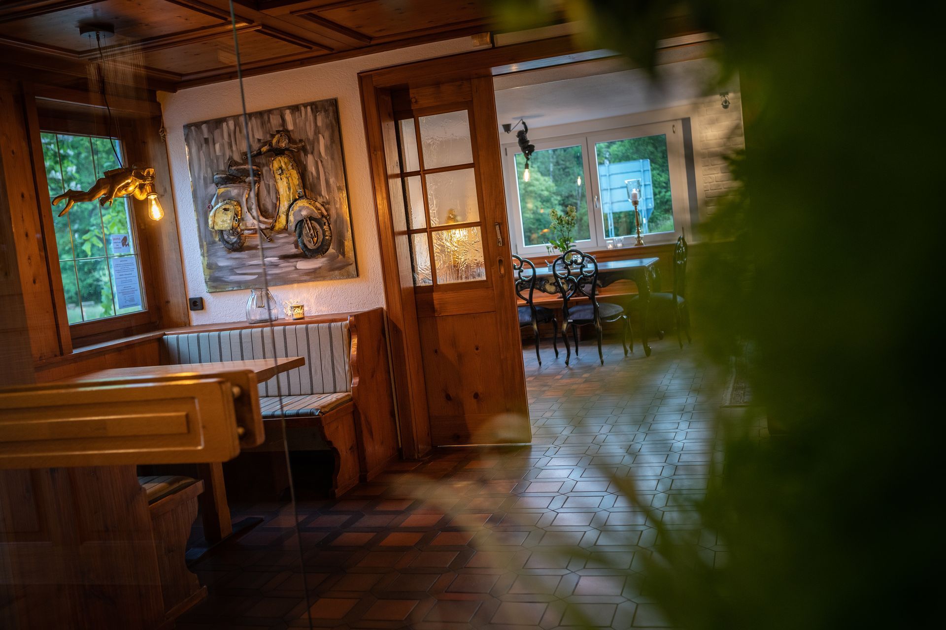 A restaurant with a wooden table and benches and a painting on the wall.