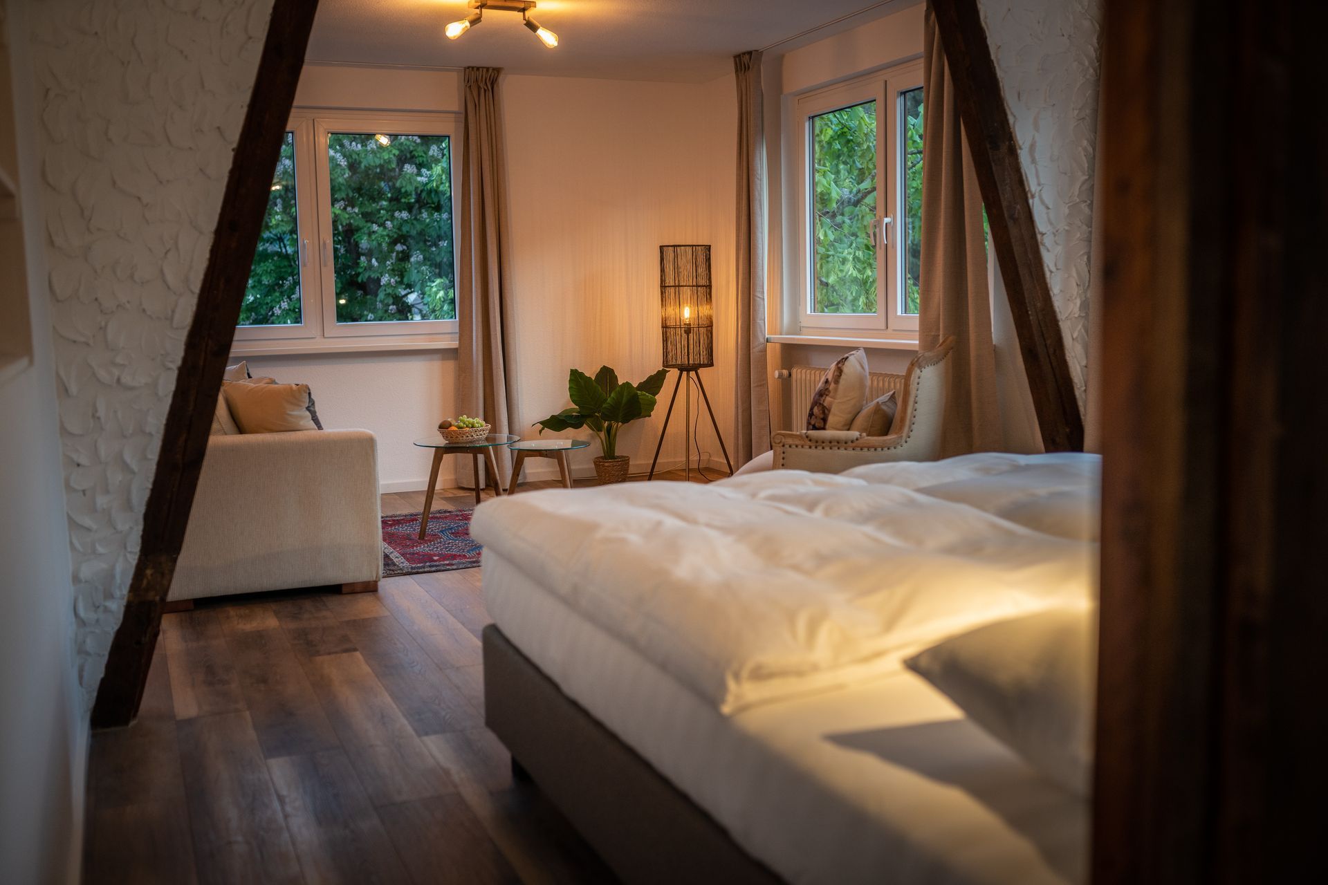 A bedroom with a bed , couch , lamp and window.