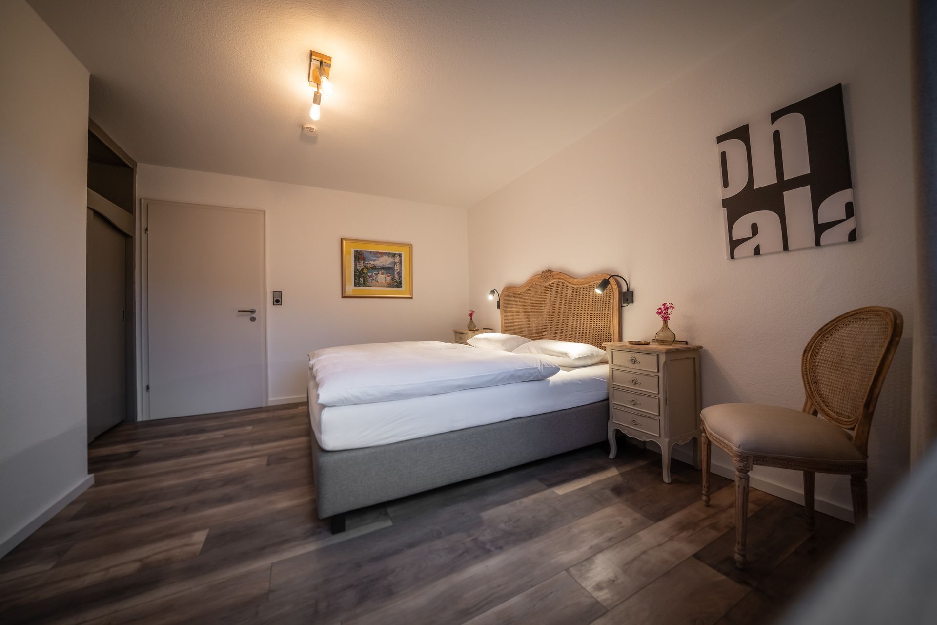 A bedroom with a bed , nightstand and chair.