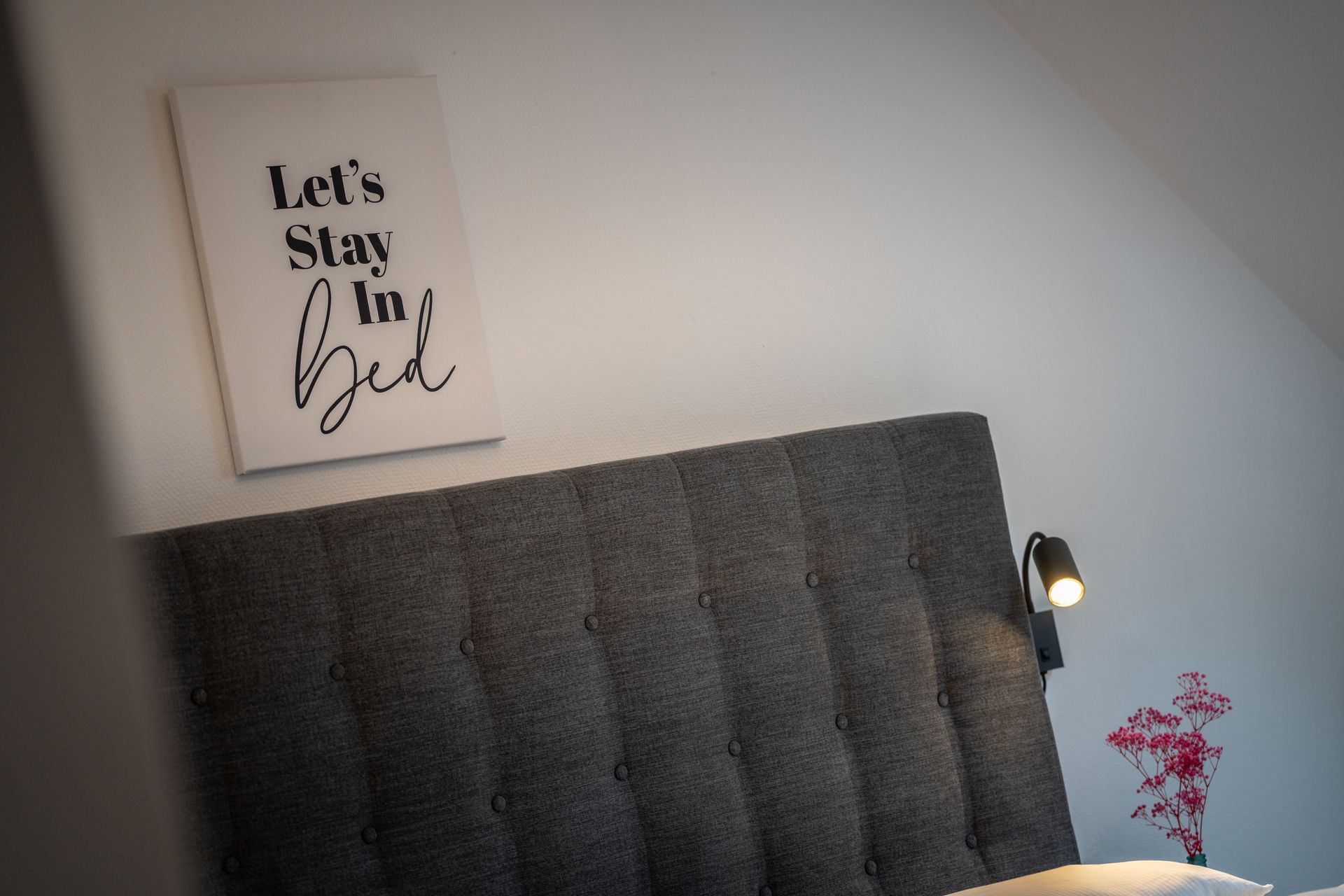 A bedroom with a bed and a sign that says let 's stay in bed