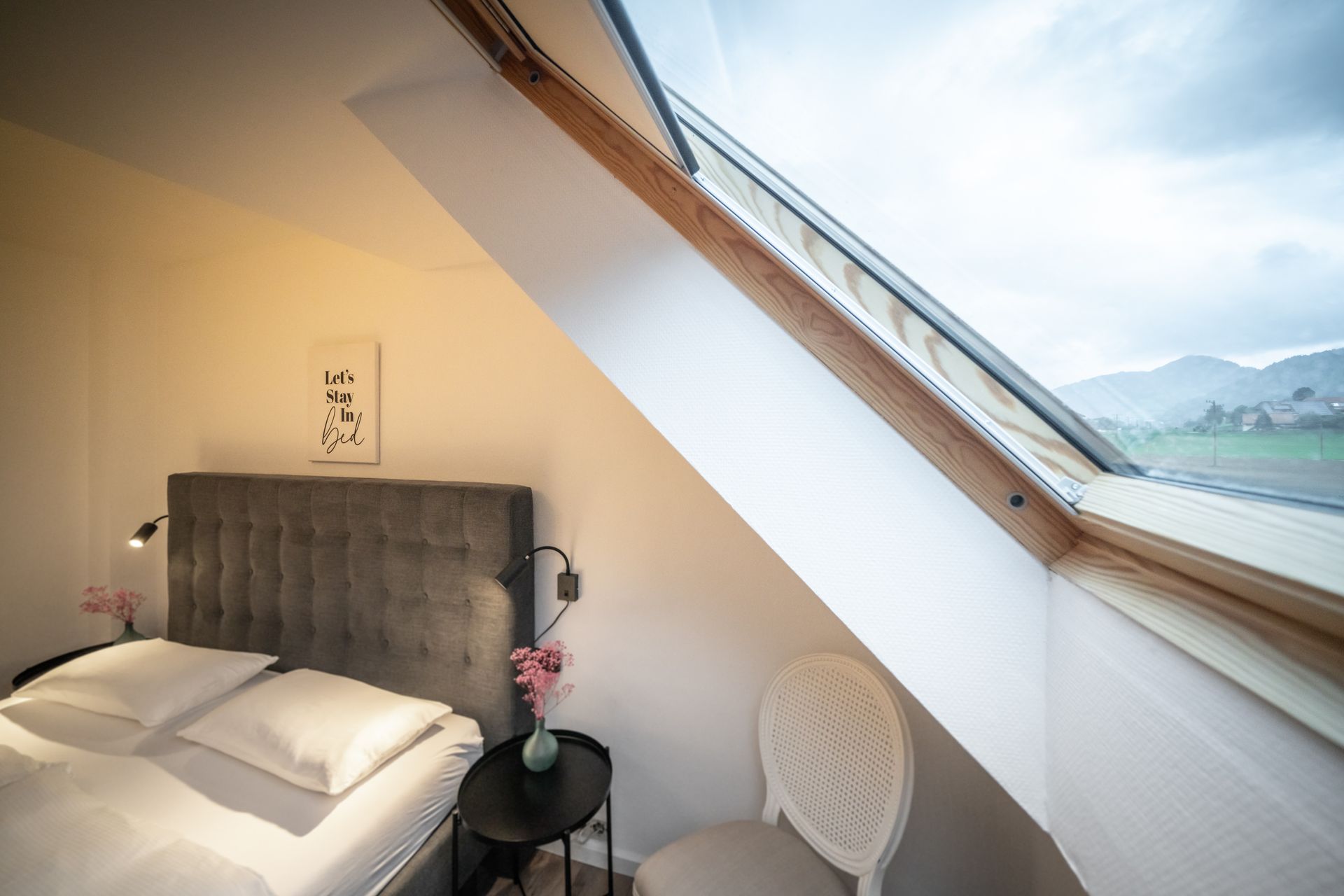 A bedroom with a bed , chair , table and window.