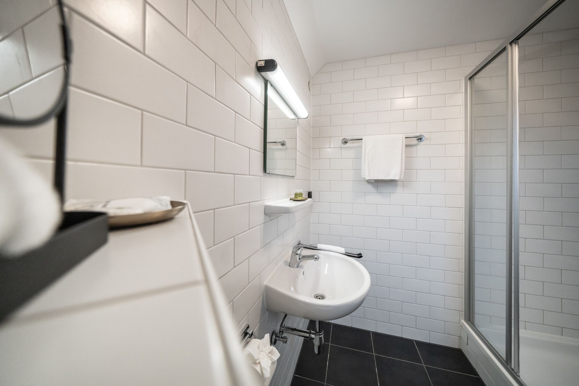 A bathroom with a sink , mirror and shower.