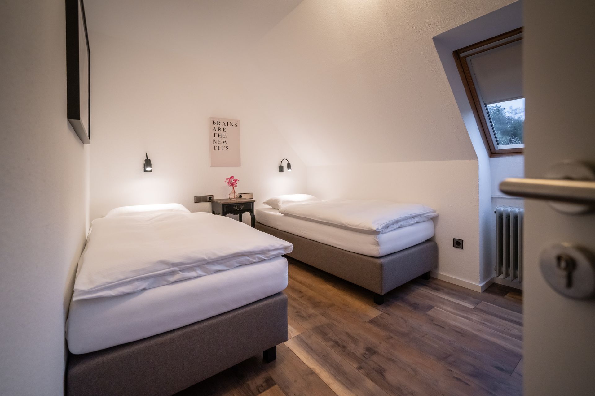 A bedroom with two beds and a window.