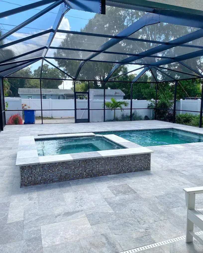 Swimming pool and spa under a screened enclosure with gray tiled patio.