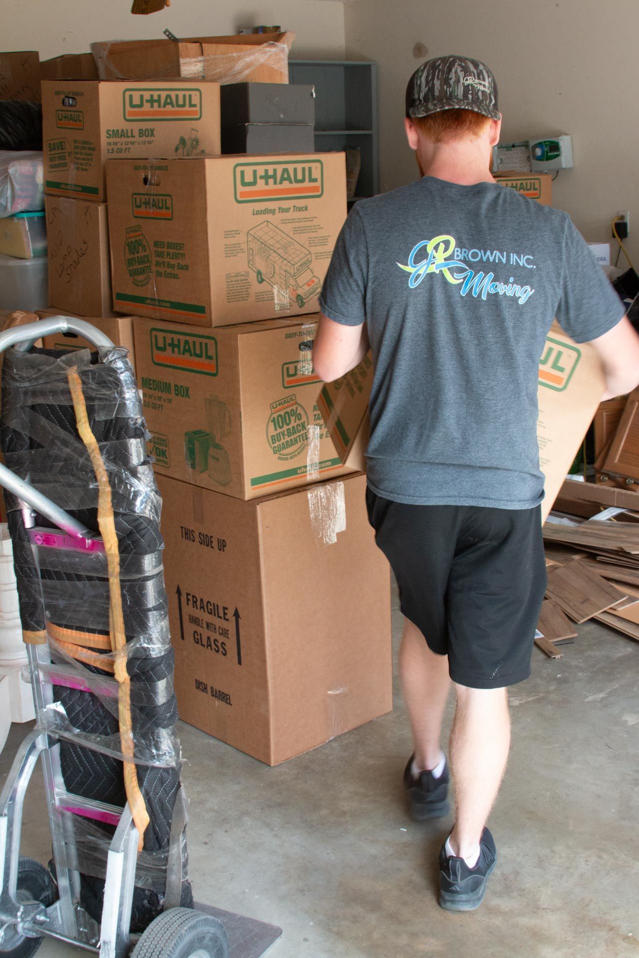 A man is carrying a cardboard box in a garage.