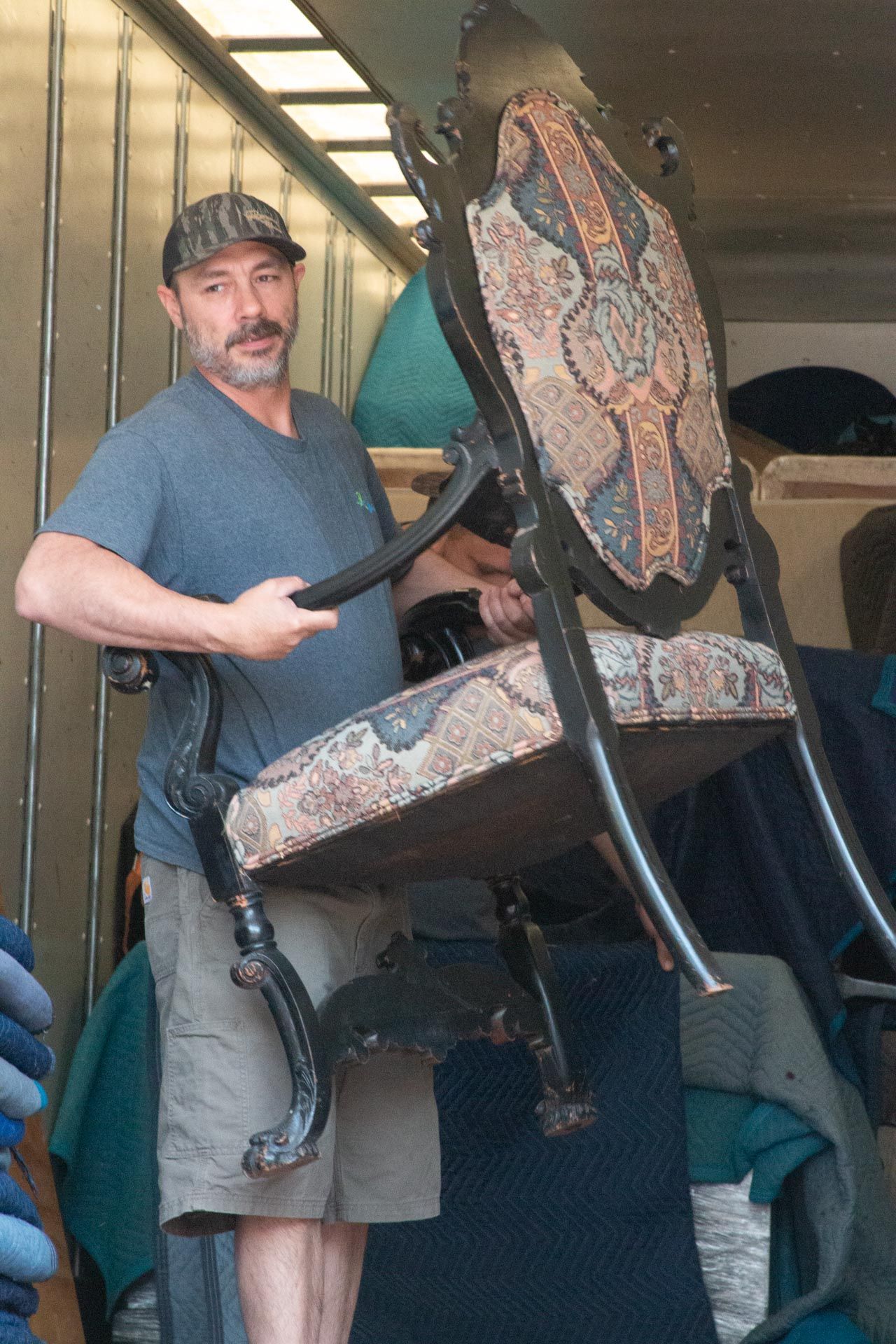 A man in a blue shirt is holding a chair in his hands