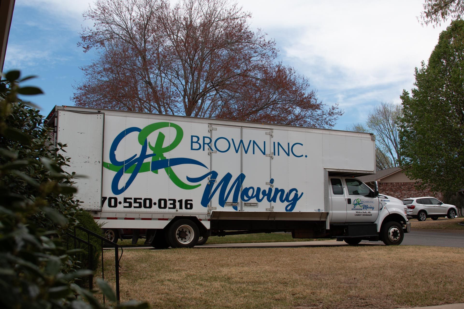 A brown inc. moving truck is parked on the side of the road