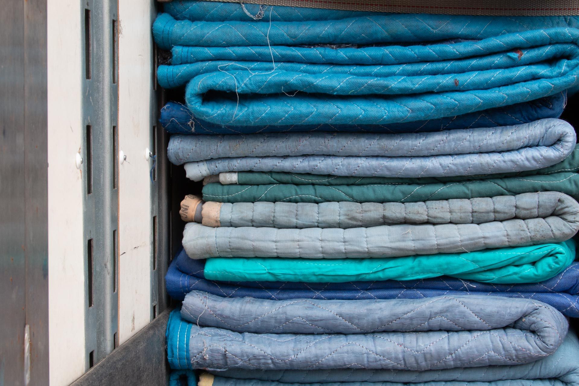A stack of blue blankets sitting on top of each other on a shelf.