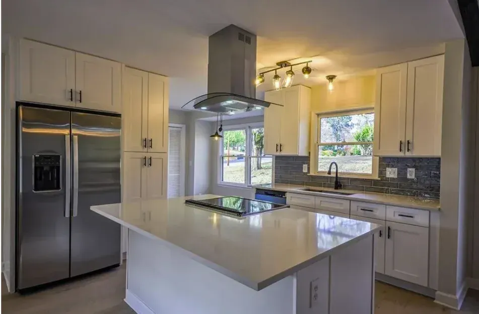 Bright modern kitchen with stainless steel appliances, white cabinets, island, and large windows