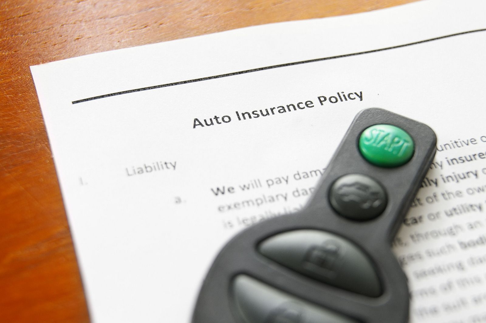 Car key fob on an auto insurance policy document on a wooden table
