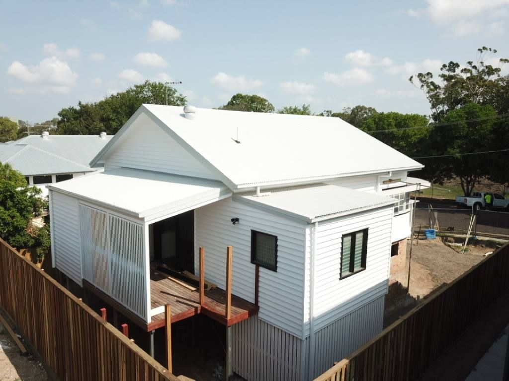 A White House With A Wooden Fence Around It โ Harrison Development Group In Surfers Paradise, QLD