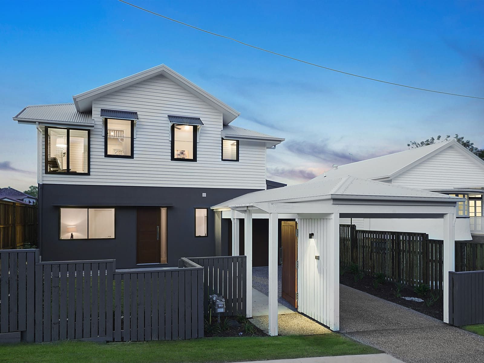 A Black And White House With A Fence In Front Of It — Harrison Development Group In Surfers Paradise, QLD
