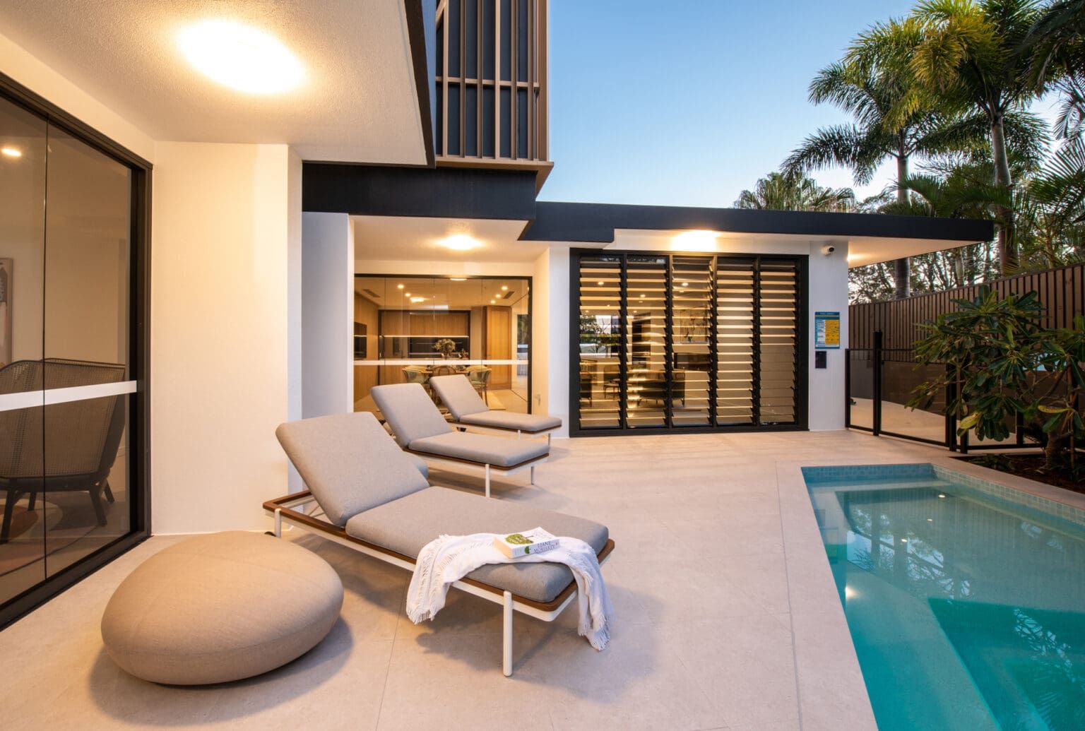 A Patio With Lounge Chairs And A Swimming Pool In Front Of A House โ Harrison Development Group In Surfers Paradise, QLD