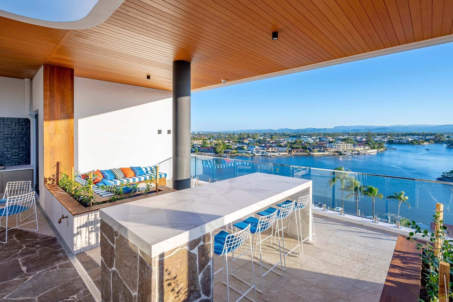 A Balcony With A Large Table And Chairs Overlooking A Body Of Water — Harrison Development Group In Surfers Paradise, QLD