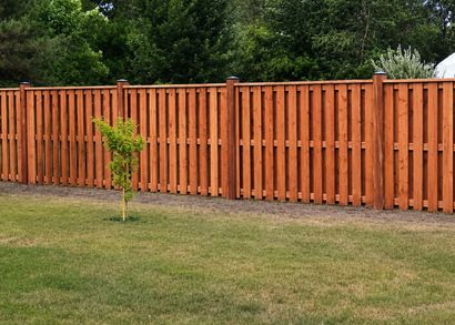 Orange wooden fence along a grassy yard with a small tree in front