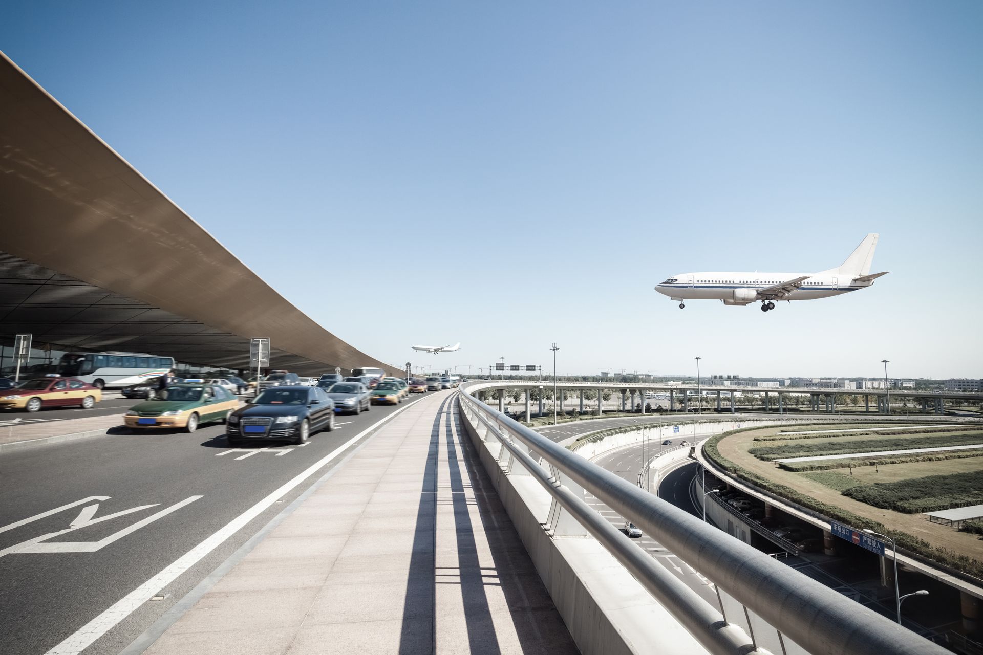 A plane is taking off from an airport with cars parked on the side of the road.