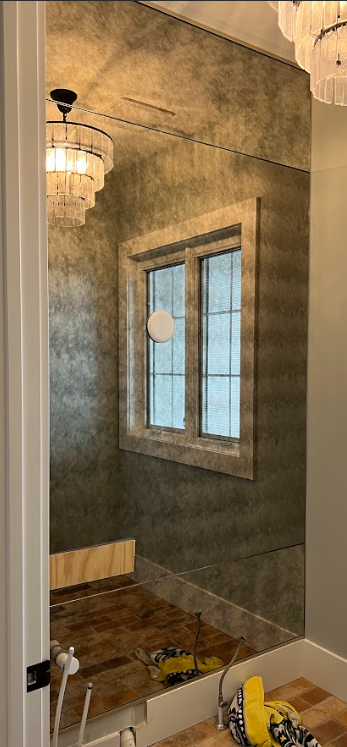 Bathroom with a large antique mirror, window, and wood floor.