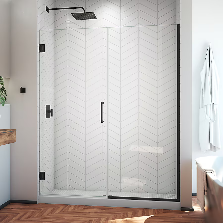 Glass shower enclosure with black hardware, white herringbone tile, and wooden floor.