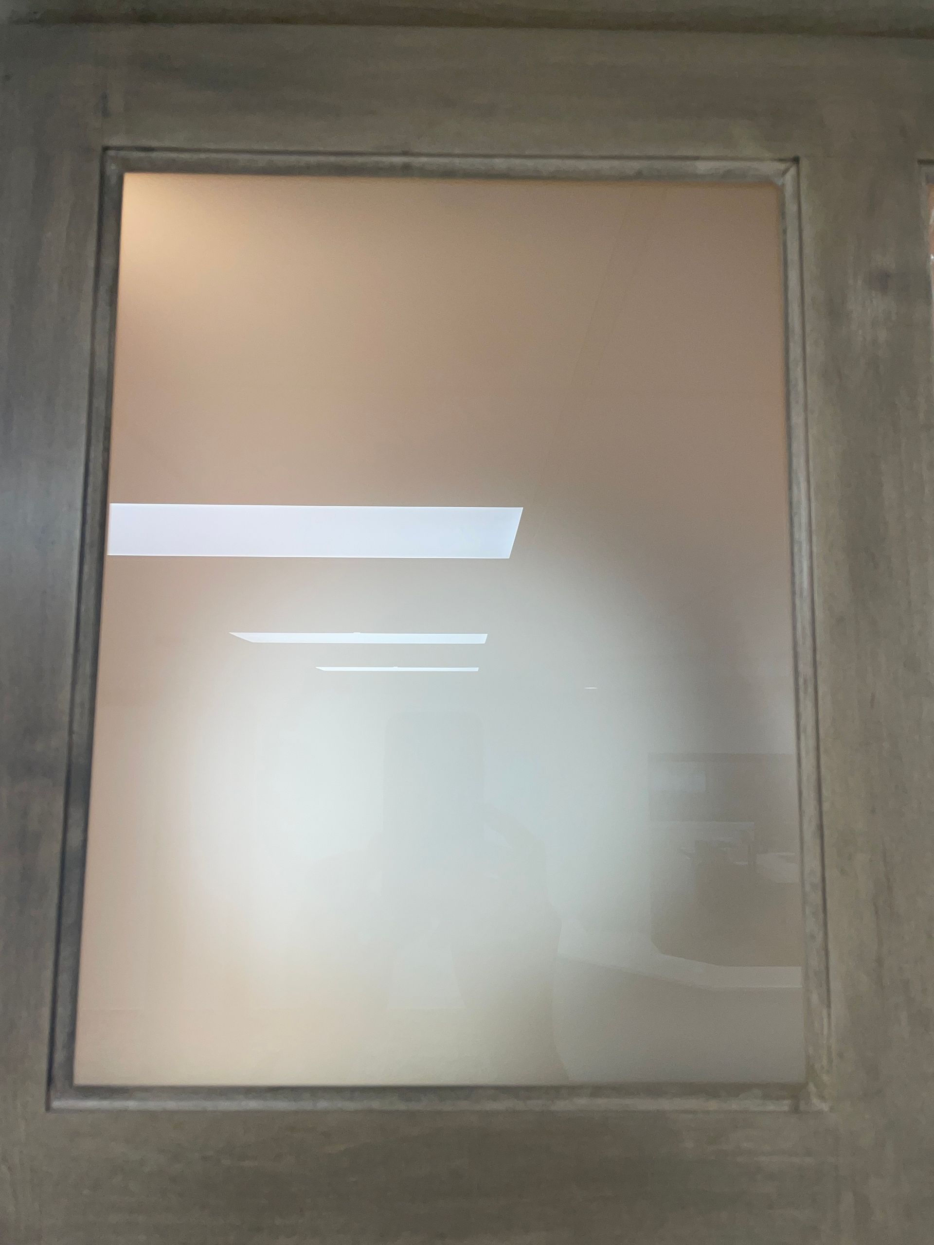 Frosted glass door with a light frame, reflecting interior lights.