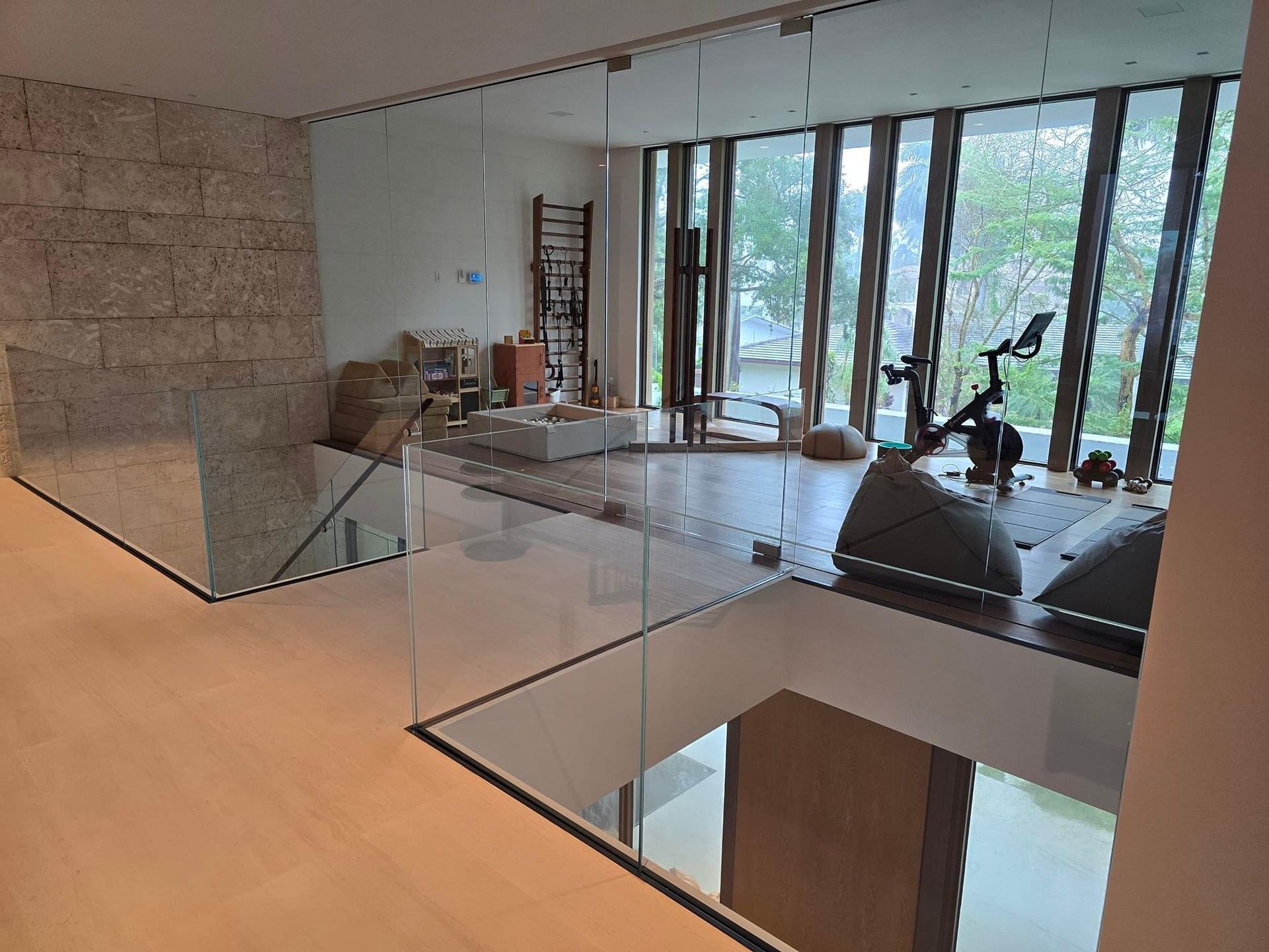 Modern home interior with glass walls, exercise equipment, and stone accents.