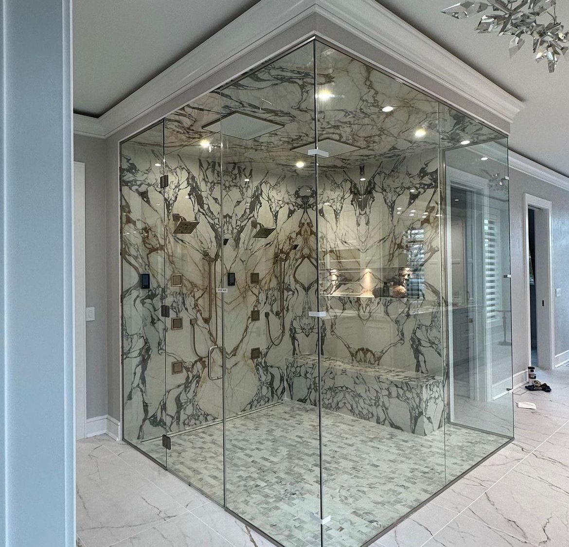 A bathroom with marble walls and a glass shower