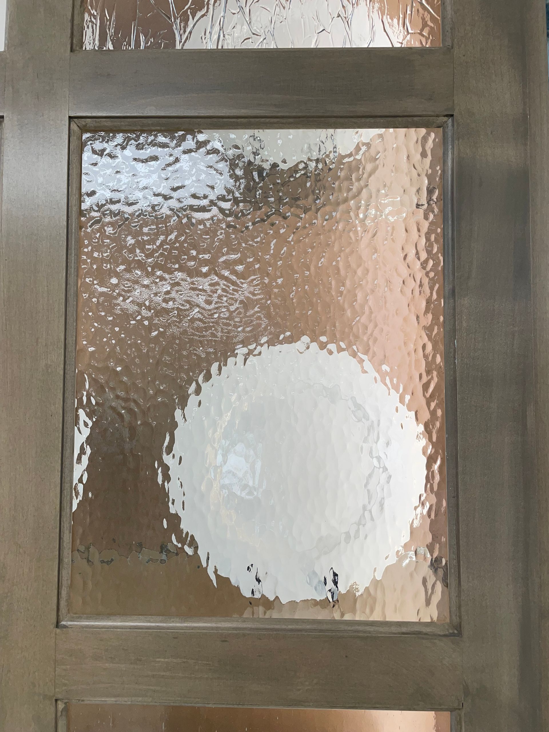 Textured glass panel in a wooden door, with a large, obscured, white circle visible.