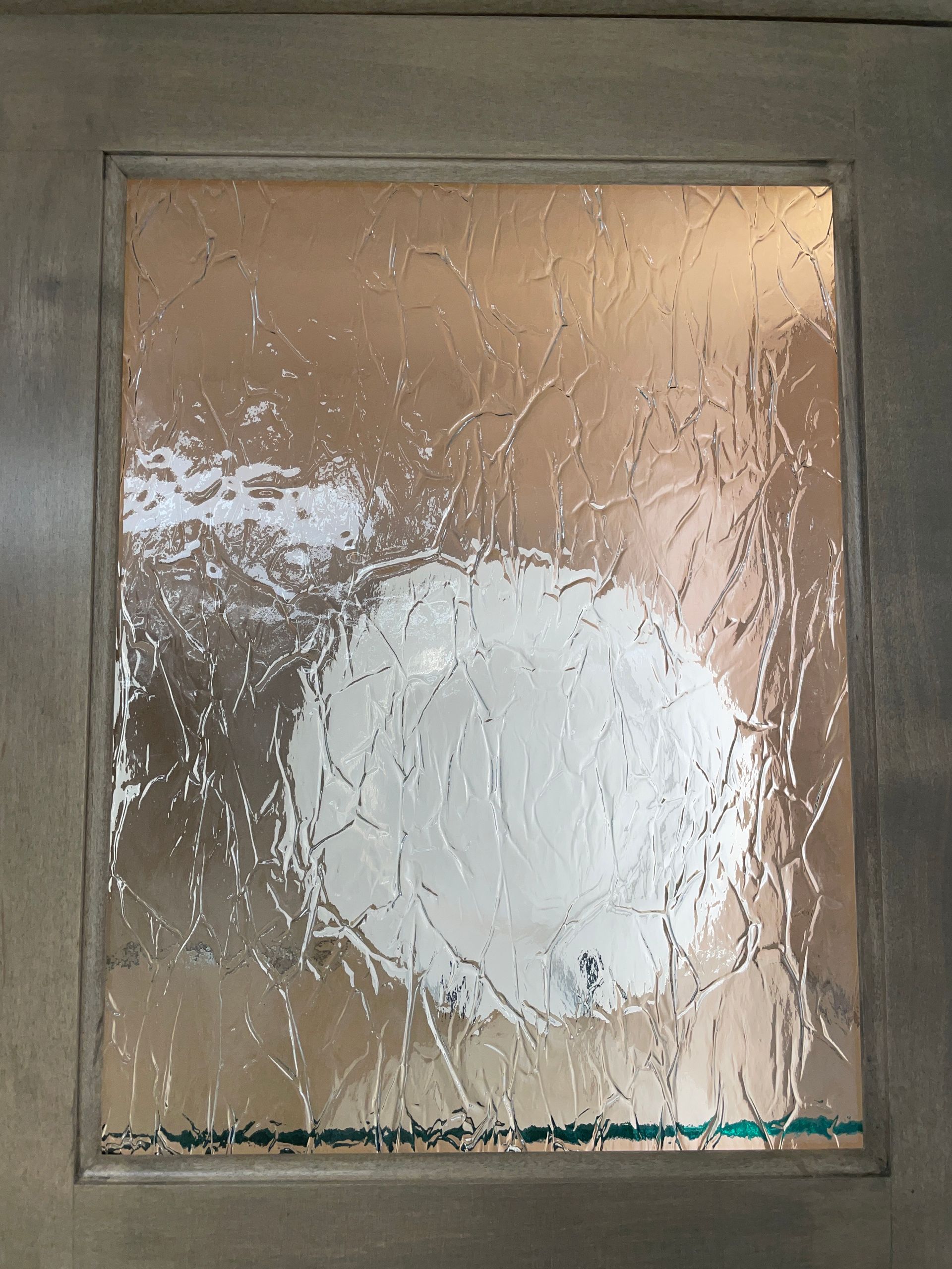 Glass door panel with textured, etched design and wooden frame.