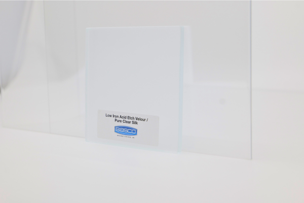 White ceramic tile with sticker, placed against a white wall and glass barrier.
