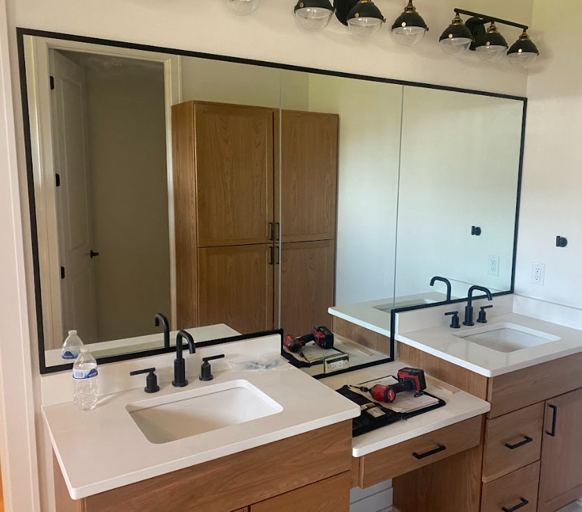 Bathroom with two vanities, large mirror, and black accents.