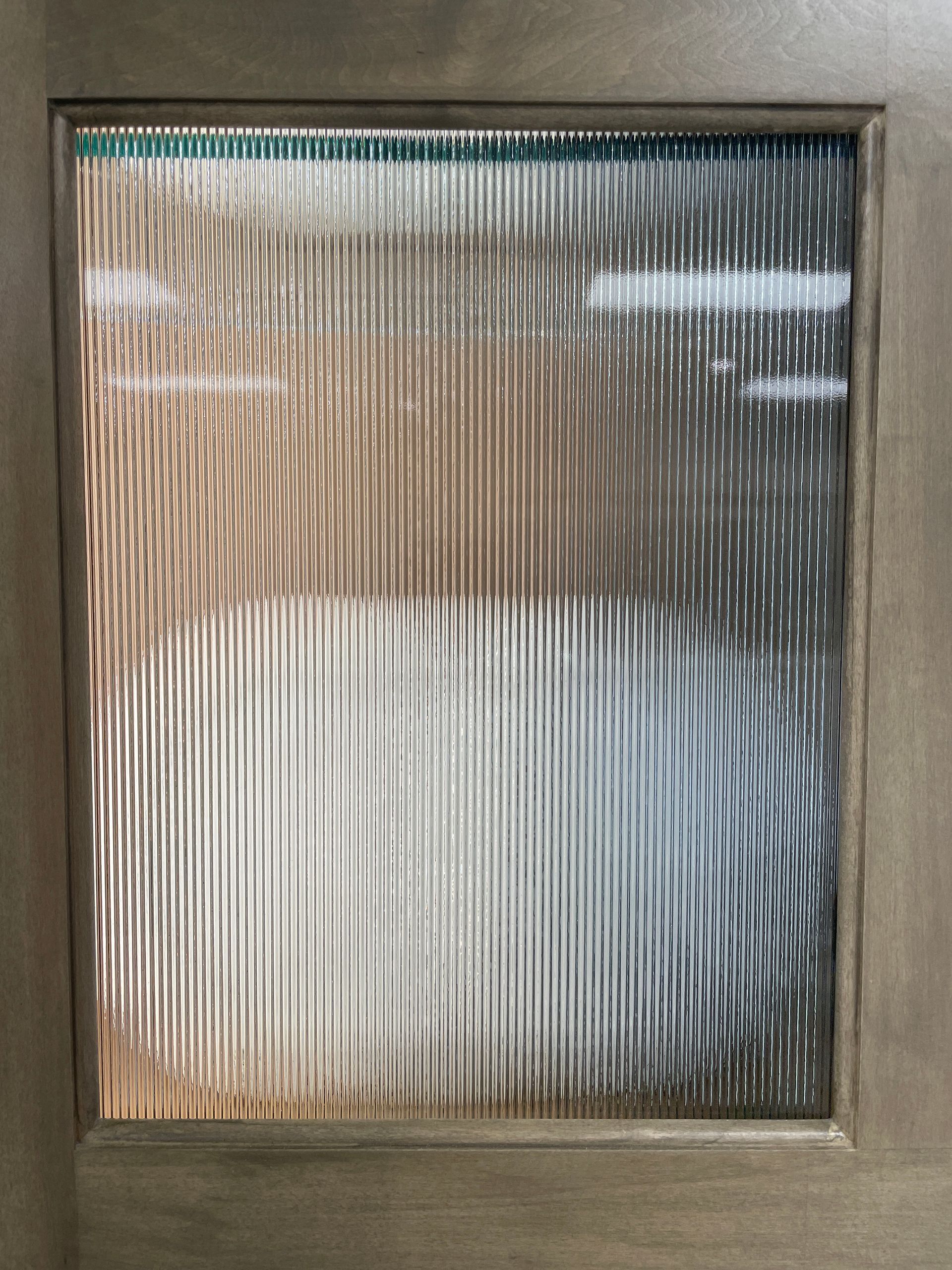Wooden door with a rectangular glass panel; the glass is textured with vertical lines.