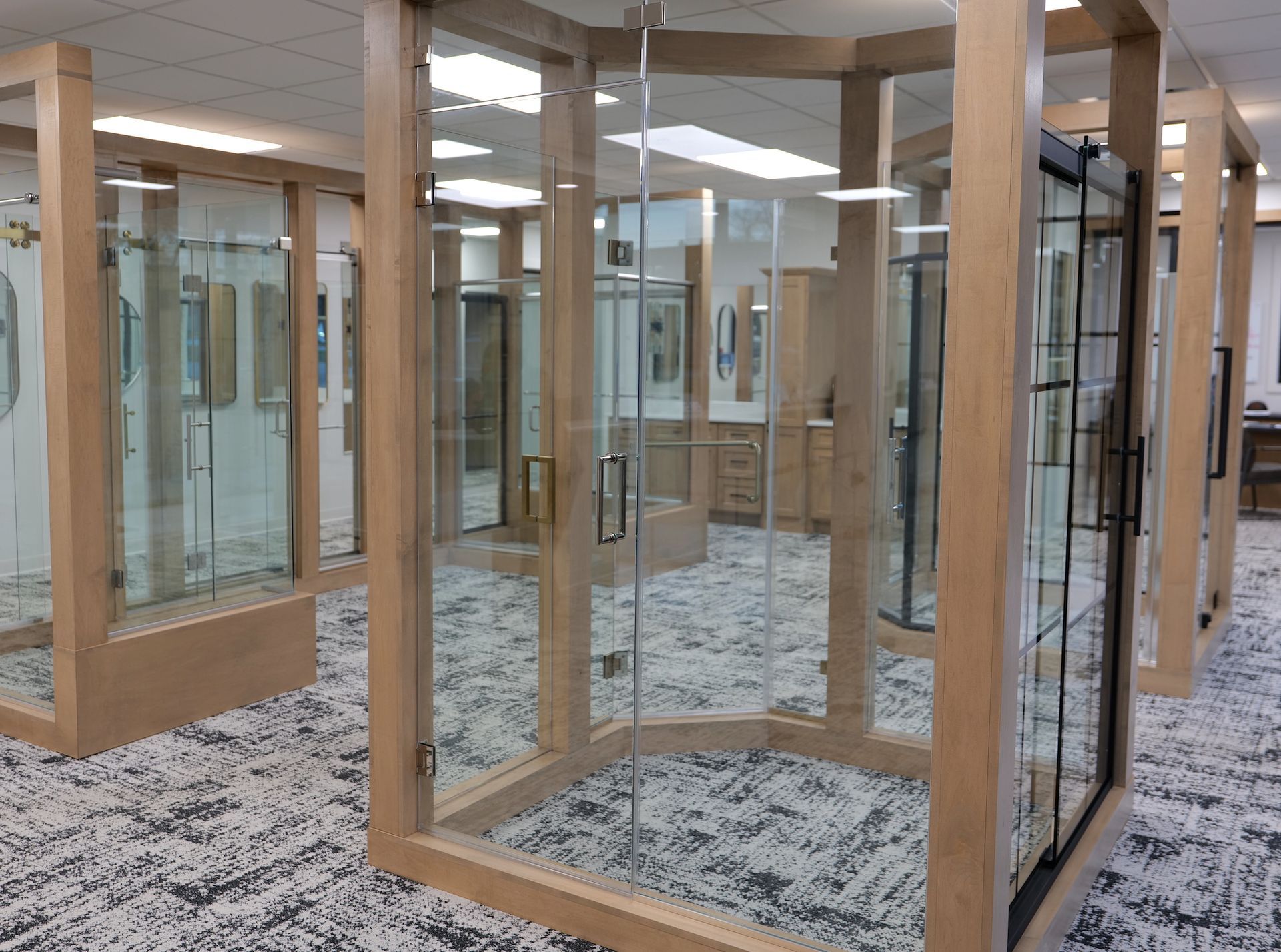 Display of glass shower enclosures with wooden frames in a showroom.