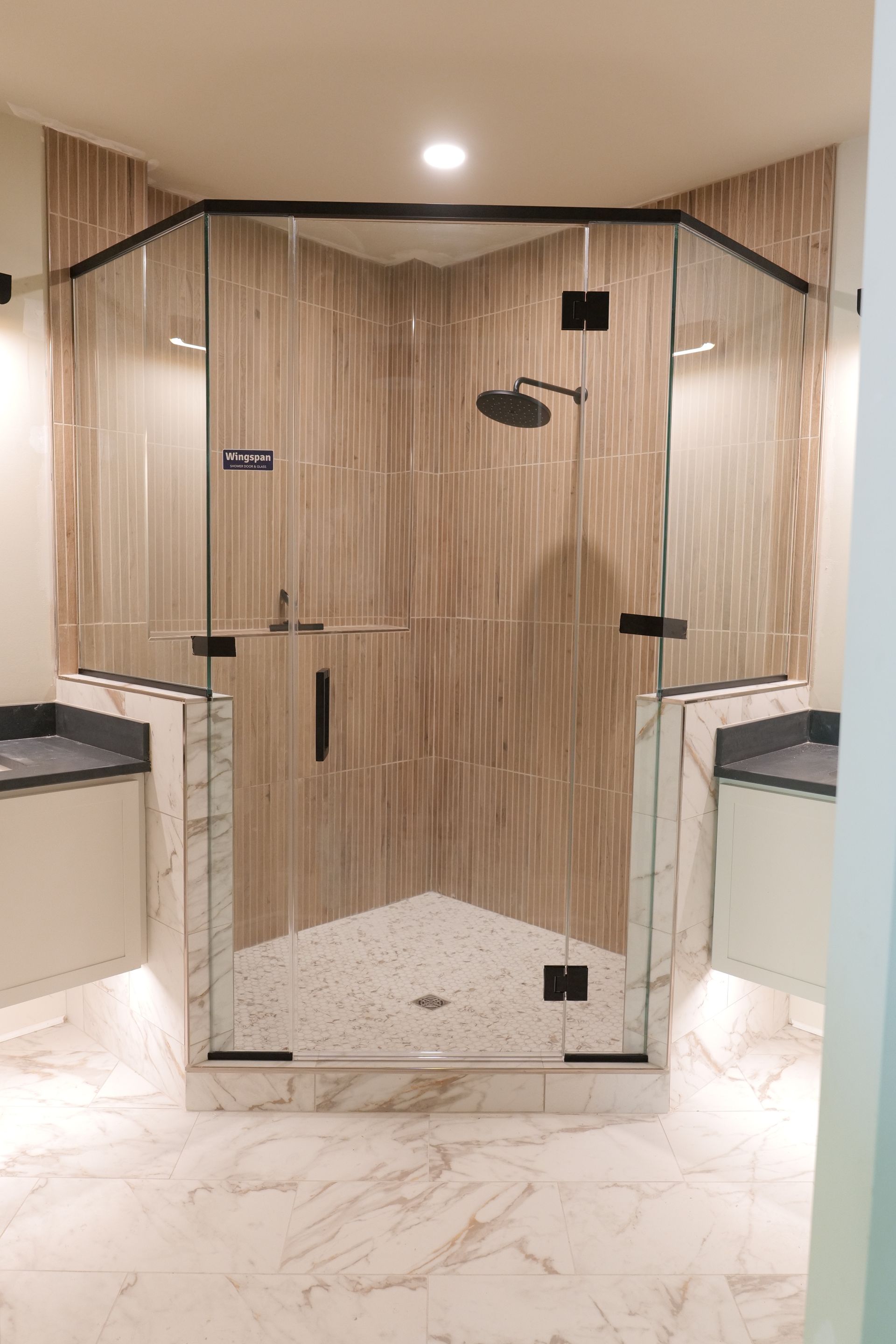 Modern bathroom with a glass shower enclosure and wooden wall tiles.