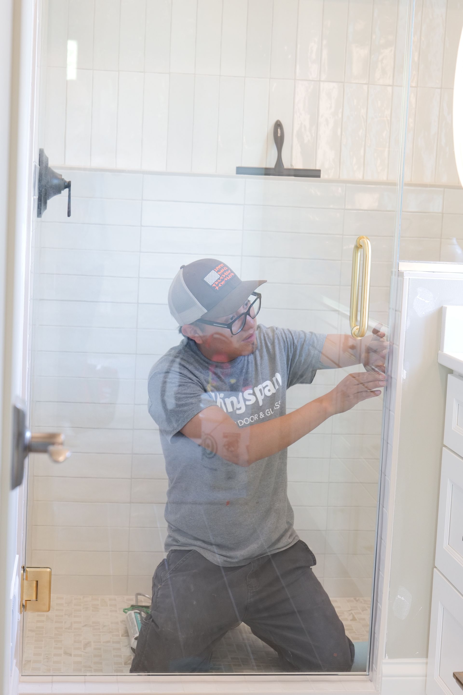 Person installing a glass shower door in a bathroom.
